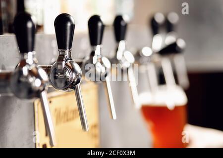 Gros plan barman main sombre Craft bière froide verser dans le verre de la grue dans le pub Banque D'Images