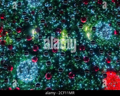 Texture d'arrière-plan sous forme de sapin décoré Avec différentes boules de Noël et illuminé avec une guirlande Banque D'Images
