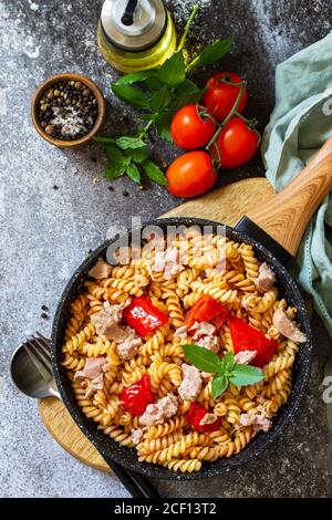 Déjeuner sain. Pâtes fusilli avec thon en conserve, poivrons rouges grillés et tomates dans une poêle sur un comptoir en pierre. Vue de dessus de l'arrière-plan de la mise à plat Banque D'Images