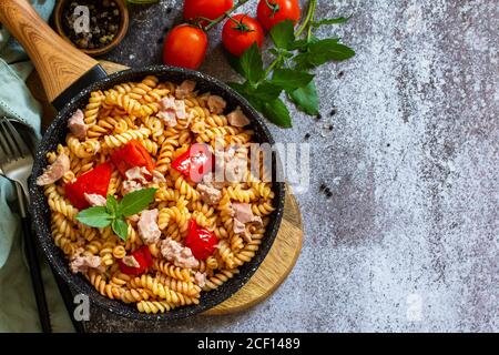 Déjeuner sain. Pâtes fusilli avec thon en conserve, poivrons rouges grillés et tomates dans une poêle sur un comptoir en pierre. Vue de dessus de l'arrière-plan de la mise à plat COP Banque D'Images