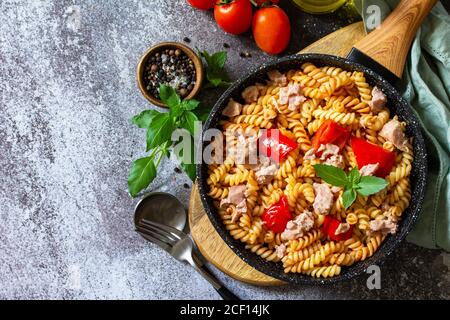 Déjeuner sain. Pâtes fusilli avec thon en conserve, poivrons rouges grillés et tomates dans une poêle sur un comptoir en pierre. Copier l'espace. Banque D'Images