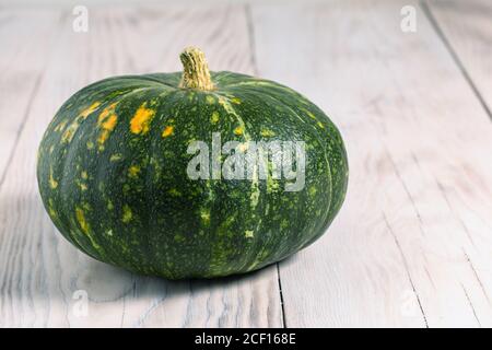 la petite citrouille verte repose sur un fond de table en bois clair Banque D'Images