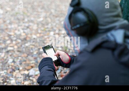 un homme assis avec son dos utilise un smartphone, regarde la liste de lecture sur le téléphone et écoute de la musique. Russie, Bashkortostan, juillet 2019. Banque D'Images