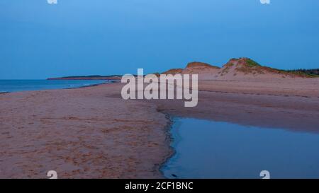 Plage déserte au crépuscule. Photo de l'heure bleue des dunes costales, dans des tons de rouge et d'azur. Cavendish Beach, parc national de l'Île-du-Prince-Édouard, Canada Banque D'Images