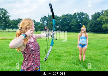 Jeune fille hollandaise visant la flèche de l'arc composé au fruit à la tête de la jeune femme Banque D'Images