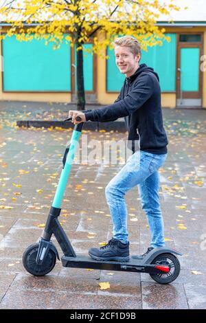 Jeune homme hollandais conduisant un scooter électrique sur la route à Finlande Banque D'Images