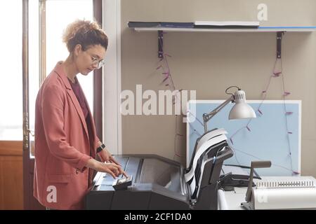 Jeune femme utilisant une machine à imprimer dans son travail elle a imprimé les documents Banque D'Images