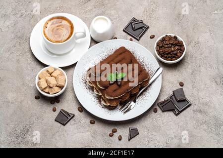 Dessert tiramisu classique, tasse de café, sucre et lait sur fond de béton Banque D'Images