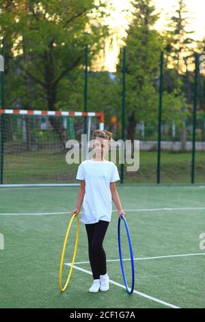 fille est engagée dans la gymnastique avec des cerceaux sur le terrain de sport. Banque D'Images