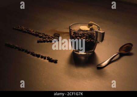 Flèche constituée de grains de café pointant vers une tasse et cuillère remplie de café Banque D'Images