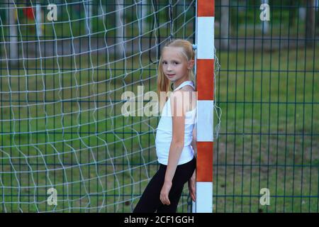 Une fille posant près d'un but de football sur un terrain de sport. Banque D'Images