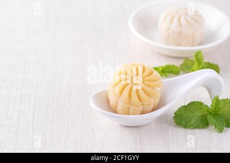 Gâteau de lune coloré en peau de neige, gâteau de lune sucré et enneigé, dessert traditionnel salé pour le festival de la mi-automne sur fond de bois clair, gros plan, lifesyl Banque D'Images