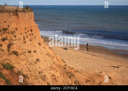 Un pêcheur à la ligne de mer pêchant sur la plage de la côte nord de Norfolk à Happisburgh, Norfolk, Angleterre, Royaume-Uni. Banque D'Images