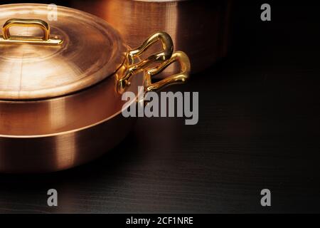 Batterie de cuisine en cuivre vintage brillant sur fond sombre Banque D'Images