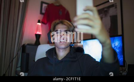 Jeune garçon souriant avec un casque qui prend son selfie avec un smartphone Banque D'Images