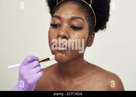 L'esthéticienne applique un masque hydratant au visage du client. Banque D'Images