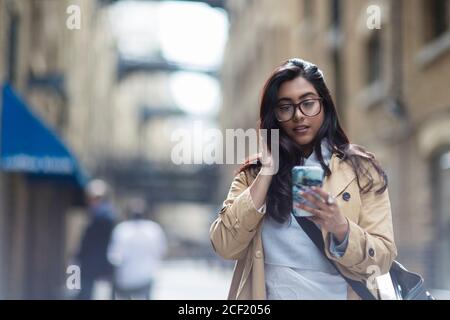 Businesswoman using smart phone on sidewalk Banque D'Images