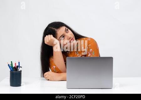 Portrait d'une jeune fille indienne perdue dans les pensées comme elle se trouve devant son ordinateur portable Banque D'Images