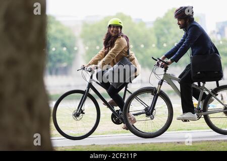 Couple heureux en casques à vélo dans le parc Banque D'Images