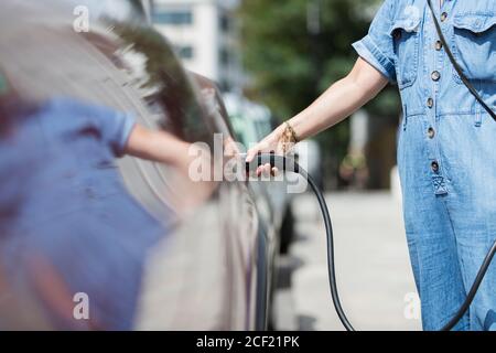 Femme recharge voiture électrique Banque D'Images