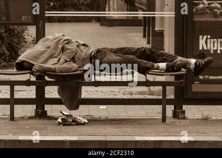 Un homme ivre dort dans une station de tramway, un homme sans domicile dort dans une station de tramway, photo en noir et blanc Banque D'Images