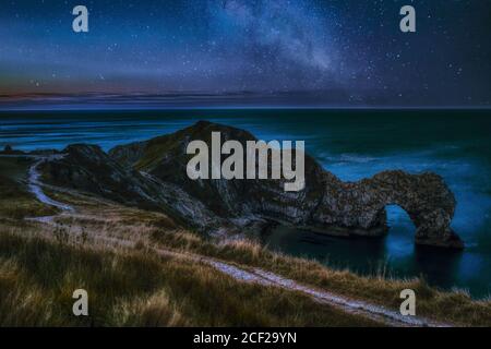 Paysage de ciel nocturne avec la galaxie de la voie lactée au-dessus de la célèbre Lieu de visite et de voyage Durdle Door English Beach on La côte jurassique de Dorset Banque D'Images