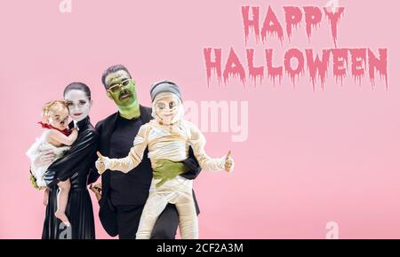 Jeune famille comme zombies sur fond rose, heure d'halloween, la circulaire avec copyspace. Black friday, cyber monday, ventes, concept d'automne. Prospectus pour votre annonce. Halloween humeur, octobre heure, effrayant et élégant. Banque D'Images