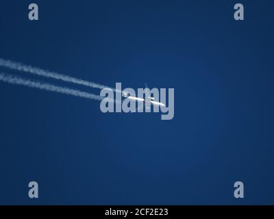 Téléplan de l'avion de ligne à double moteur Emirates volant à haute altitude dans un ciel bleu clair avec des contrailles Banque D'Images