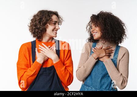 Portrait de belles multinationales femmes en combinaison souriant et tenant mains sur coffres isolés sur fond blanc Banque D'Images