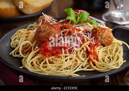 Spaghetti et boulettes de viande avec sauce tomate et parmesan une assiette à dîner noire Banque D'Images
