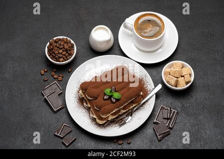 Dessert tiramisu classique, tasse de café, sucre et lait sur fond de béton Banque D'Images