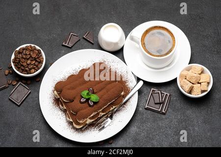 Dessert tiramisu classique, tasse de café, sucre et lait sur fond de béton Banque D'Images