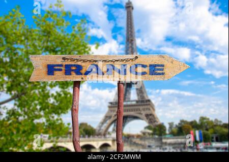 France flèche de bois sur la route signe contre la tour Eiffel en arrière-plan de printemps. Concept Voyage en France. Banque D'Images