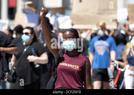 Une femme noire portant un masque facial et un débardeur du Minnesota tient un poing levé lors d'une manifestation Black Lives Matter à Trafalgar Square, Londres Banque D'Images