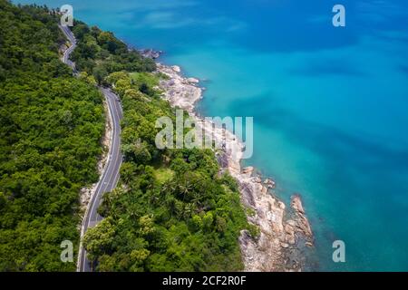Vue aérienne de la route entre le cocotier et le grand océan en journée à Nakhon si Thammarat, Thaïlande Banque D'Images