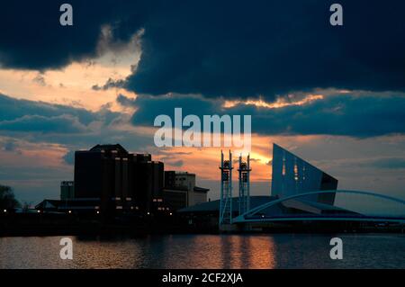 Coucher de soleil sur le bâtiment Quay West, l'Imperial War Museum North et la passerelle Millennium (Lowry), Salford Quays, Manchester, Royaume-Uni. Banque D'Images