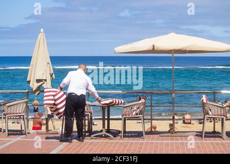 Las Palmas, Grande Canarie, Îles Canaries, Espagne. 3 septembre 2020. Un serveur met des tables au restaurant donnant sur la plage de la ville de Las Palmas sur la Grande Canarie alors que l'Allemagne rejoint le Royaume-Uni et ajoute les îles Canaries à sa liste de destinations de quarentine, citant la montée récente des cas Covid. Les îles Canaries ont vu une augmentation des infections à Covid 19. Les statistiques d'août pour les îles Canaries ont été de 4,469 nouveaux cas (moyenne de 144 cas par jour), avec 70% de ceux sur la Grande Canarie, avec Las Palmas le point chaud. Banque D'Images