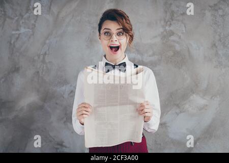 Portrait d'elle belle-belle-belle-attrayante intelligente stupéfait joyeuse fille ondulée-cheveux lecture périodique de grandes nouvelles isolées sur gris béton Banque D'Images