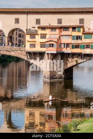 Homme en barque ramer sur le fleuve Arno sous le pont Ponte Vecchio à Florence, Italie avec un reflet du pont. Banque D'Images