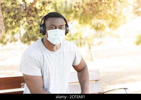 Portrait d'un jeune homme noir sur un visage protecteur masquez l'écoute de musique avec un casque Banque D'Images