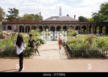 Des adolescents qui se posent à côté de la fontaine Sibirica de William Pye qui gaillira un étang dans le jardin de l'iris, Holland Park, à l'ouest de Londres, Royaume-Uni. Banque D'Images