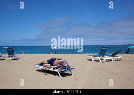 03 septembre 2020, Espagne, Las Palmas de Gran Canaria: Un homme allongé sur une chaise longue se protège du soleil avec un T-shirt sur la plage de Las Canteras. En raison de l'augmentation du nombre de nouvelles infections de corona, le gouvernement allemand a maintenant émis un avertissement de voyage pour les îles Canaries - et donc pour l'ensemble de l'Espagne. Photo: Manuel Navarro/dpa Banque D'Images