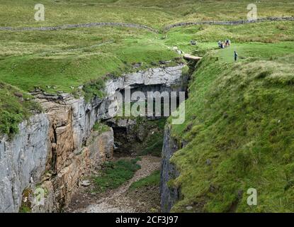 Hull Pothole Pot dans les landes près de Horton à Ribblesdale, dans le North Yorkshire, au Royaume-Uni, avec des gens à proximité pour l'échelle Banque D'Images