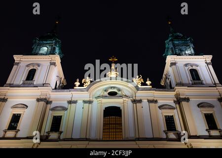 Varsovie, Pologne avec l'église de la Sainte-Croix façade catholique romaine tour extérieure près le soir nuit sombre illuminée de noir Banque D'Images