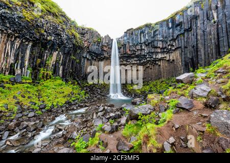 Svartifoss cascade exposition longue de la rivière vue grand angle sur Sentier dans le parc national de Skaftafell en Islande vue de la chute de l'eau au large de la falaise dans le vert summ Banque D'Images