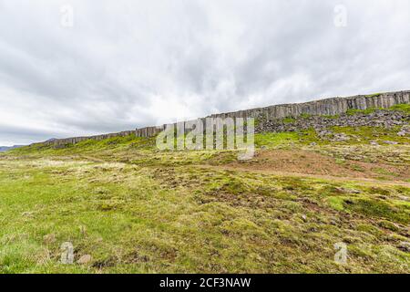 Gerduberg Basalt colonnes grand angle vue paysage à Snaefellsnes Islande avec l'herbe verte le jour d'été, nuages orageux et personne Banque D'Images