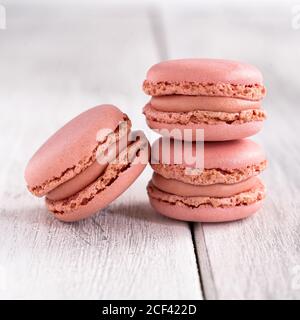 Macarons roses et savoureux empilés sur une surface blanche en bois Banque D'Images