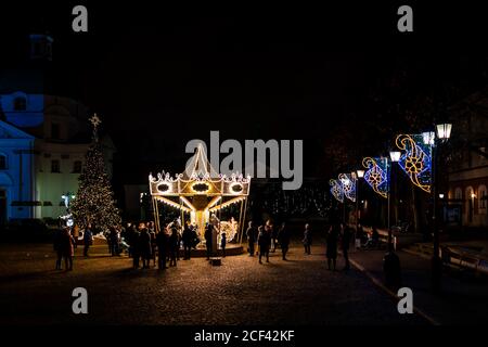 Varsovie, Pologne - 26 décembre 2019 : nouvelle place du marché de la ville de rynek avec manège de joyeux-Go-round la nuit avec beaucoup de gens illuminés lumières Banque D'Images