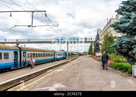 Rivne, Ukraine - 25 juillet 2018: Voies ferrées avec ancienne gare en Ukraine occidentale avec lignes électriques personnes marchant sur la plate-forme et Banque D'Images