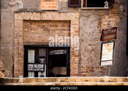 San Gimignano, Italie - 27 août 2018 : rue dans le village de Toscane pendant la journée d'été et panneau ouvert avec menu pour le restaurant trattoria chiribiri Banque D'Images